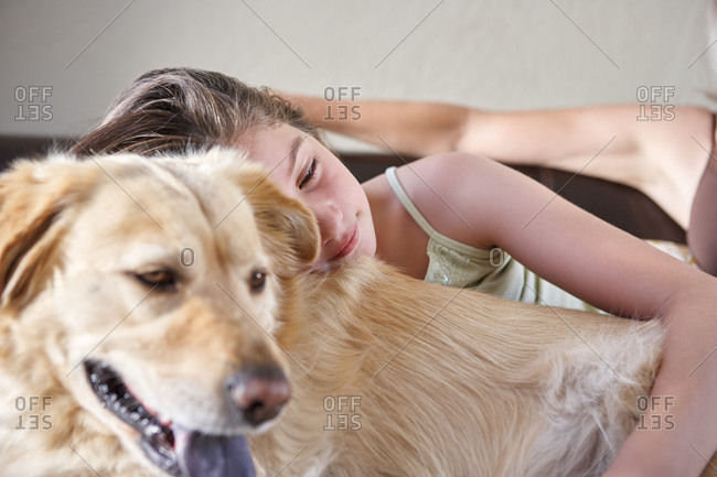 Little girl snuggling with dog in living room