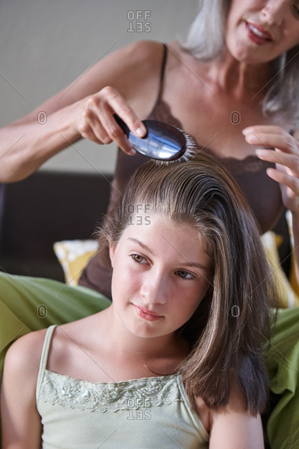 Mother brushing daughter's hair in living room
