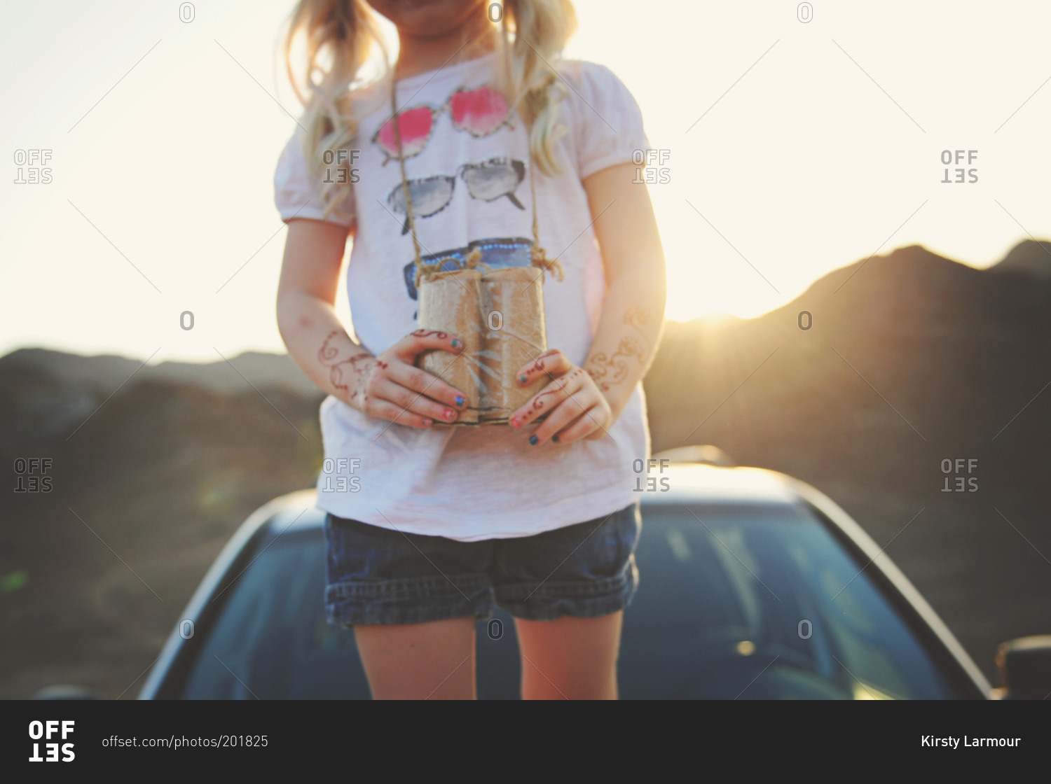 Girl standing on a car with cardboard binoculars
