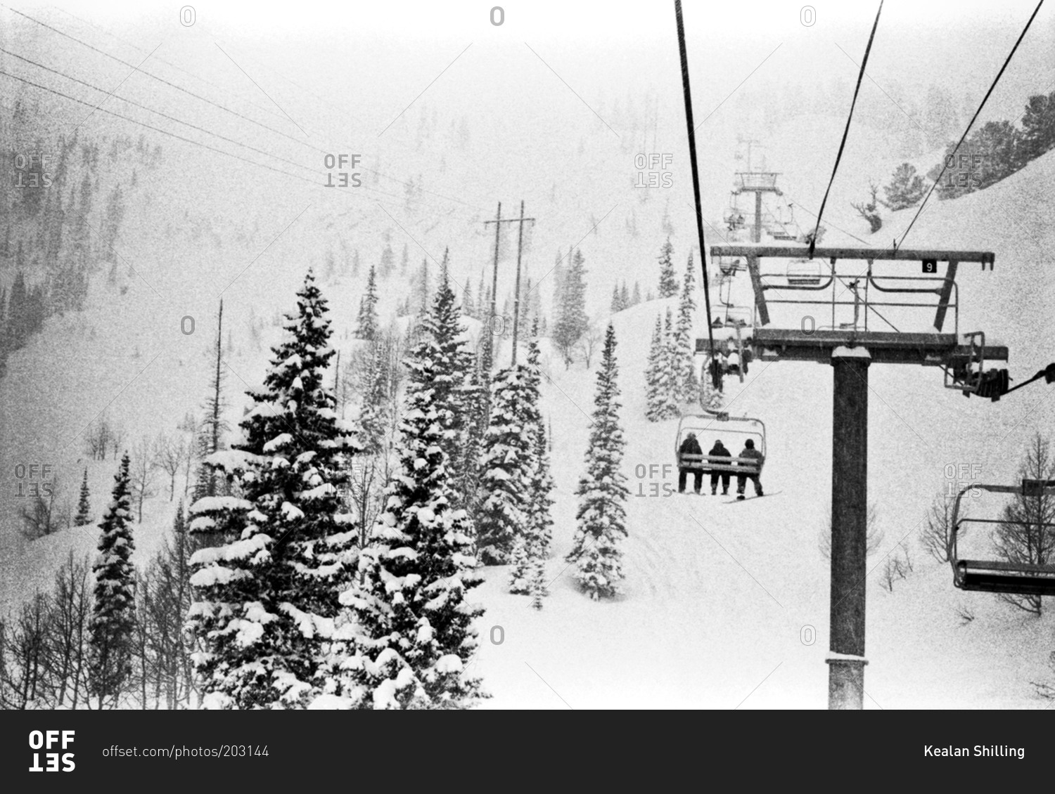 People riding ski lift up snowy slope