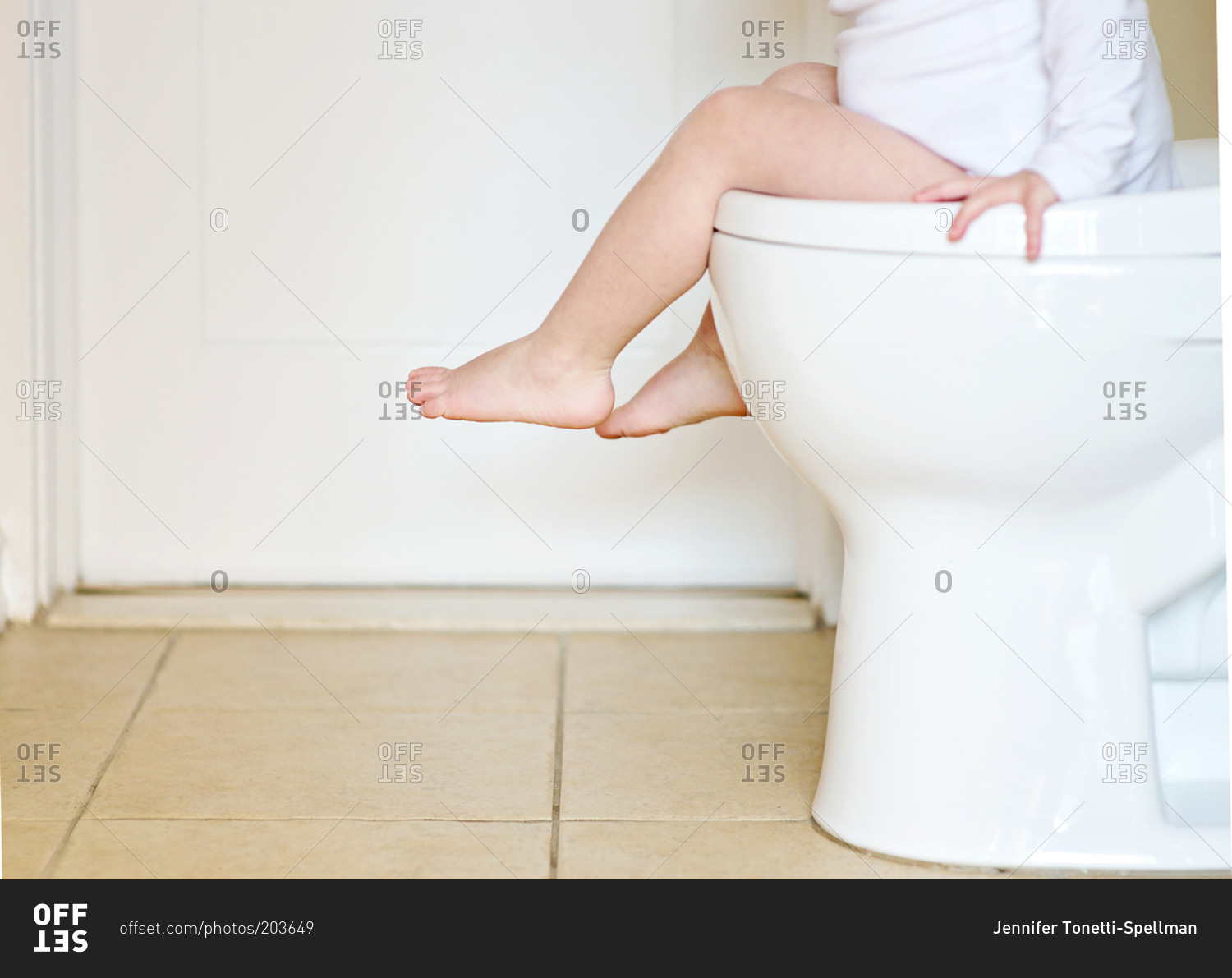 Child Sitting In Toilet And Holding Tissue Roll Stock 