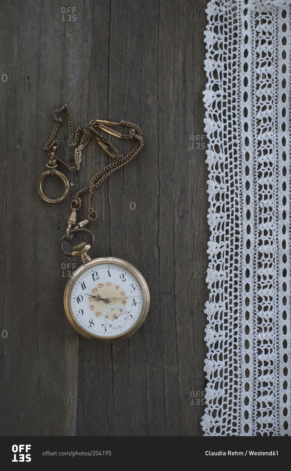 Old pocket watch and lace on dark wood