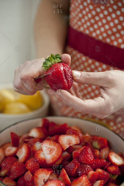 A woman cutting a strawberry