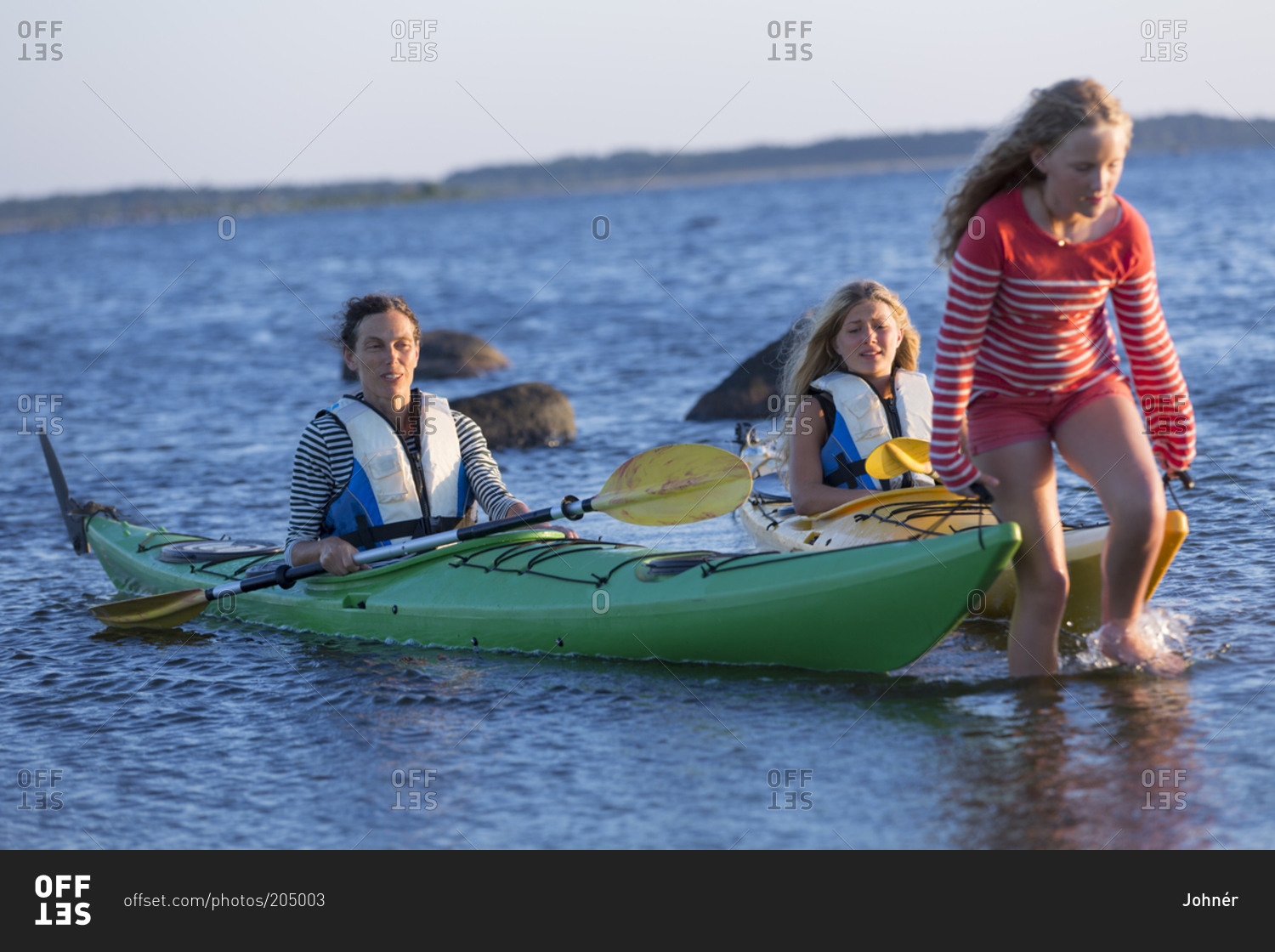 Girl pulling kayaks into the sea