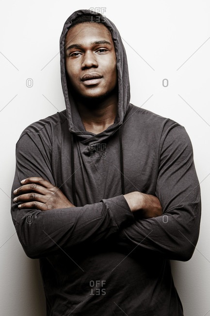 Portrait of young man wearing hoodie with his arms crossed stock photo -  OFFSET