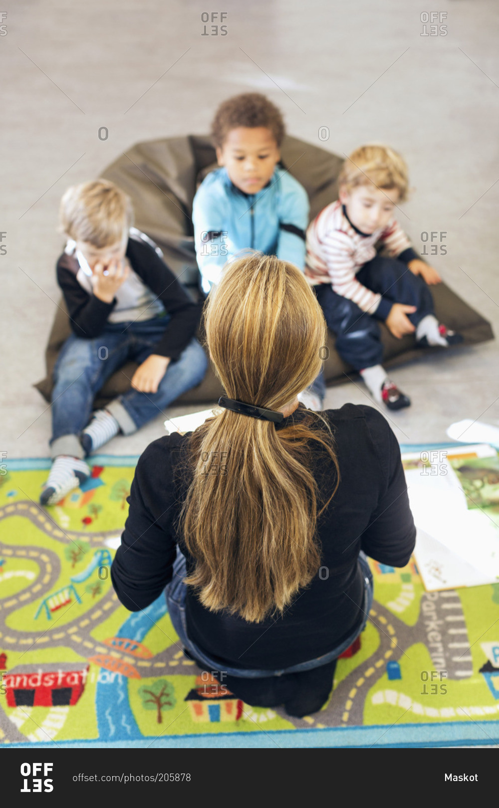 High angle view of teacher sitting in front of children at kindergarten