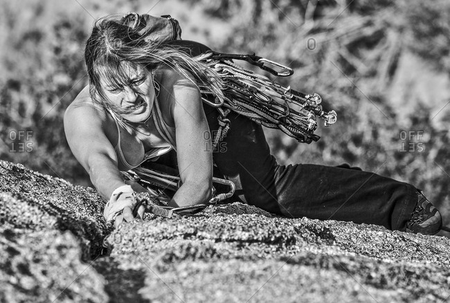 A rock climber pulls herself up a rock wall