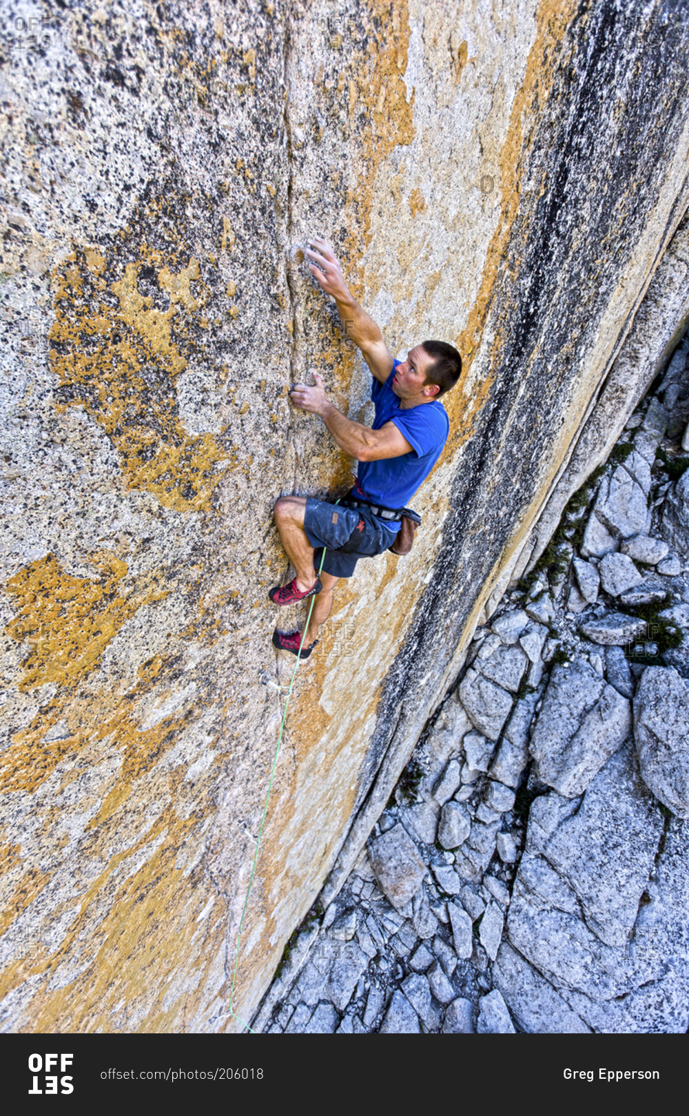 A rock climber heads up a vertical rock wall