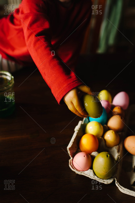 Child placing an Easter egg into an egg carton