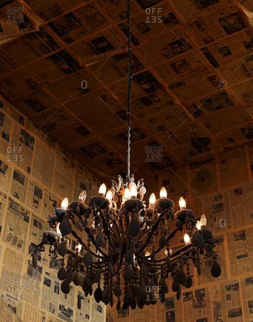 An old-fashioned chandelier hangs in a newspaper-lined room