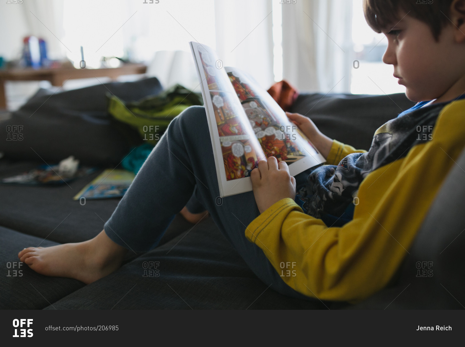 Young boy reading a graphic novel on a couch