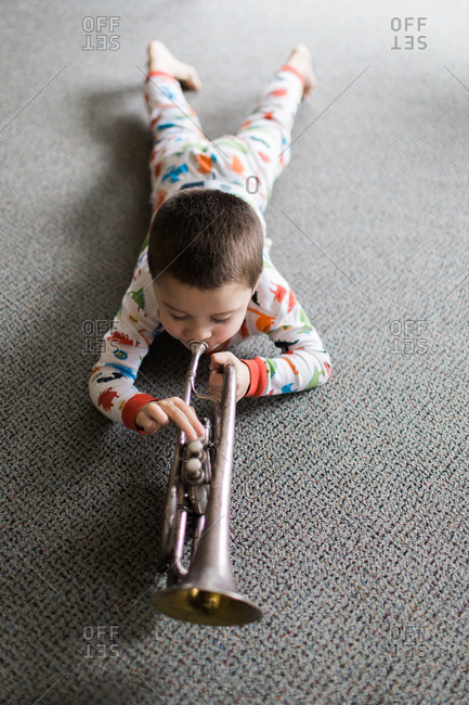 Young boy practicing playing trumpet in living room at home Stock