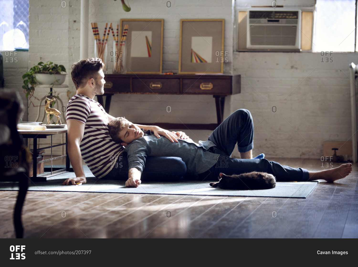 Gay couple lounging in loft with cat
