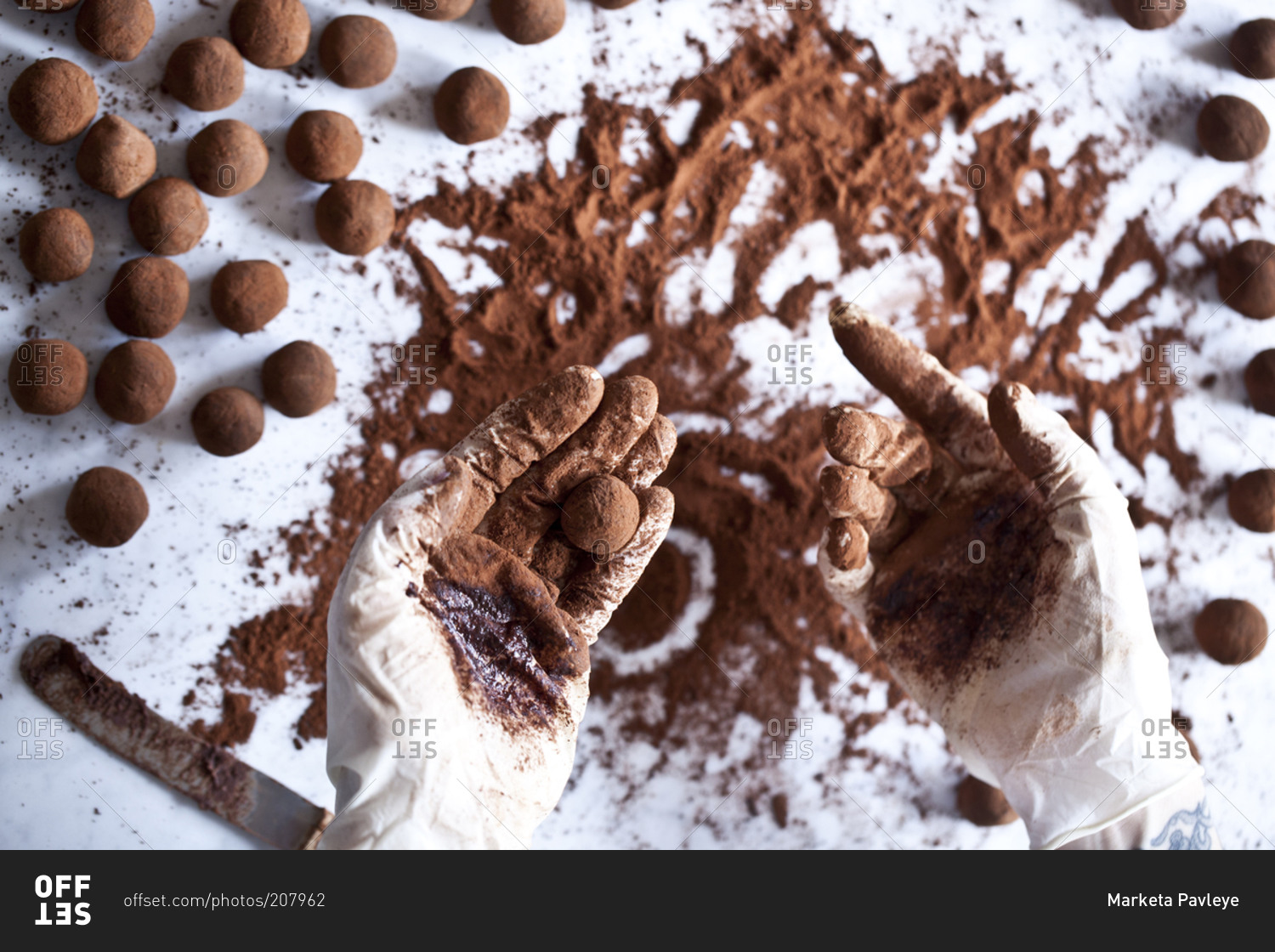 A cook rolls truffles in cocoa