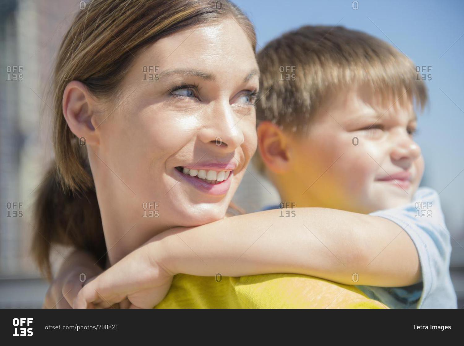 Happy mother giving her son a piggyback ride in the city stock photo