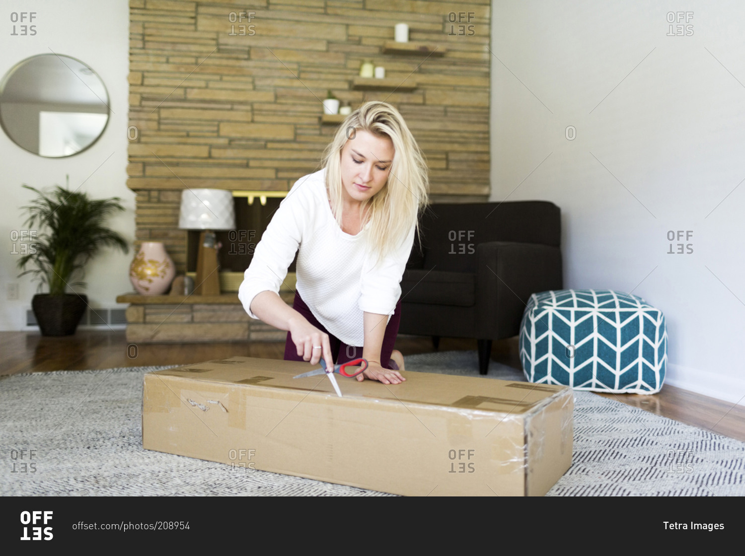 Young woman opening box with scissors