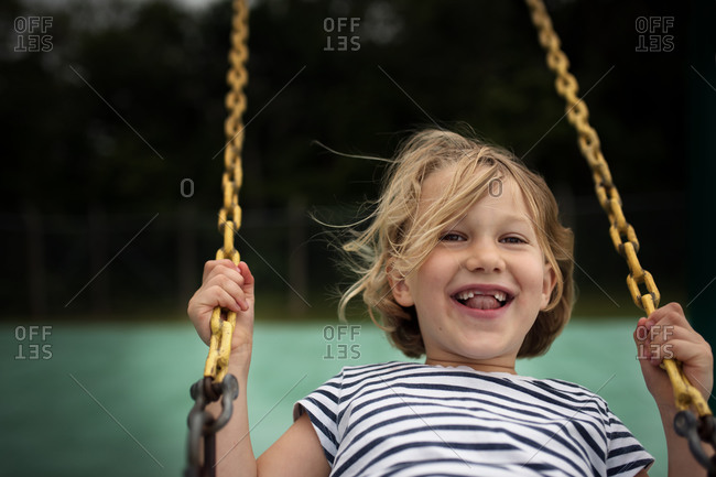 Girl with missing teeth smiling on swing