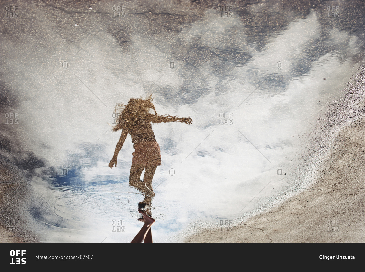 Young girl reflected in a puddle on pavement