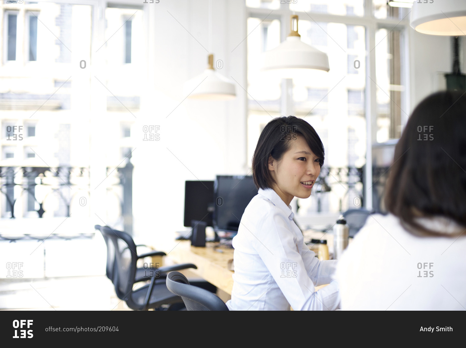 Office worker talking to her co-worker in an bright open work space
