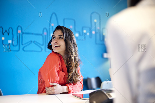 Young employee of a creative agency listens to a colleague speak in a meeting