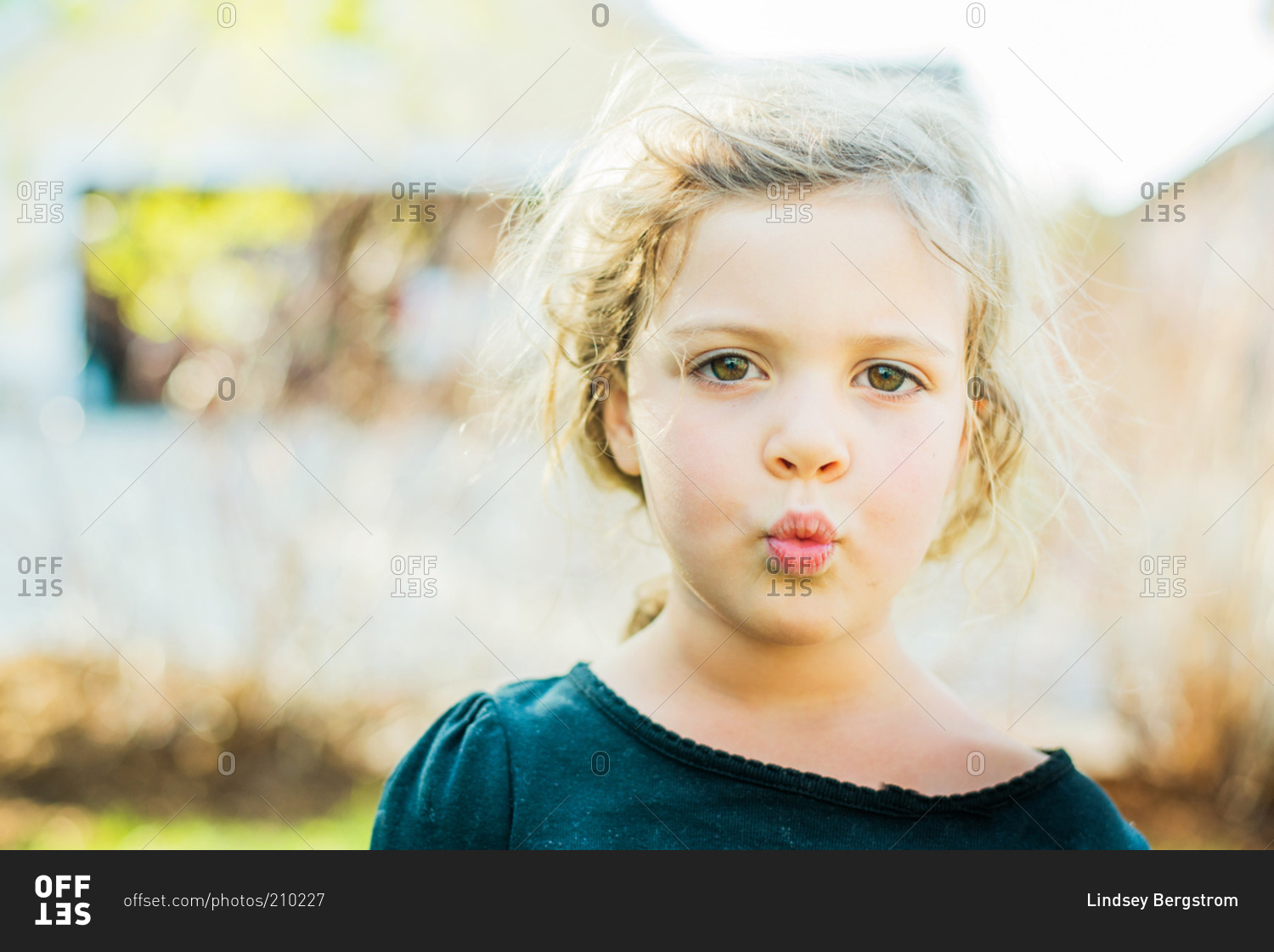 Portrait of young girl whistling in yard stock photo - OFFSET