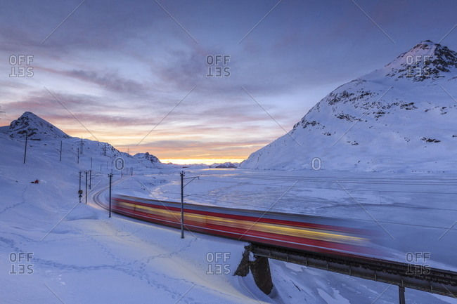 A red train passes through Graubunden, Swiss Alps