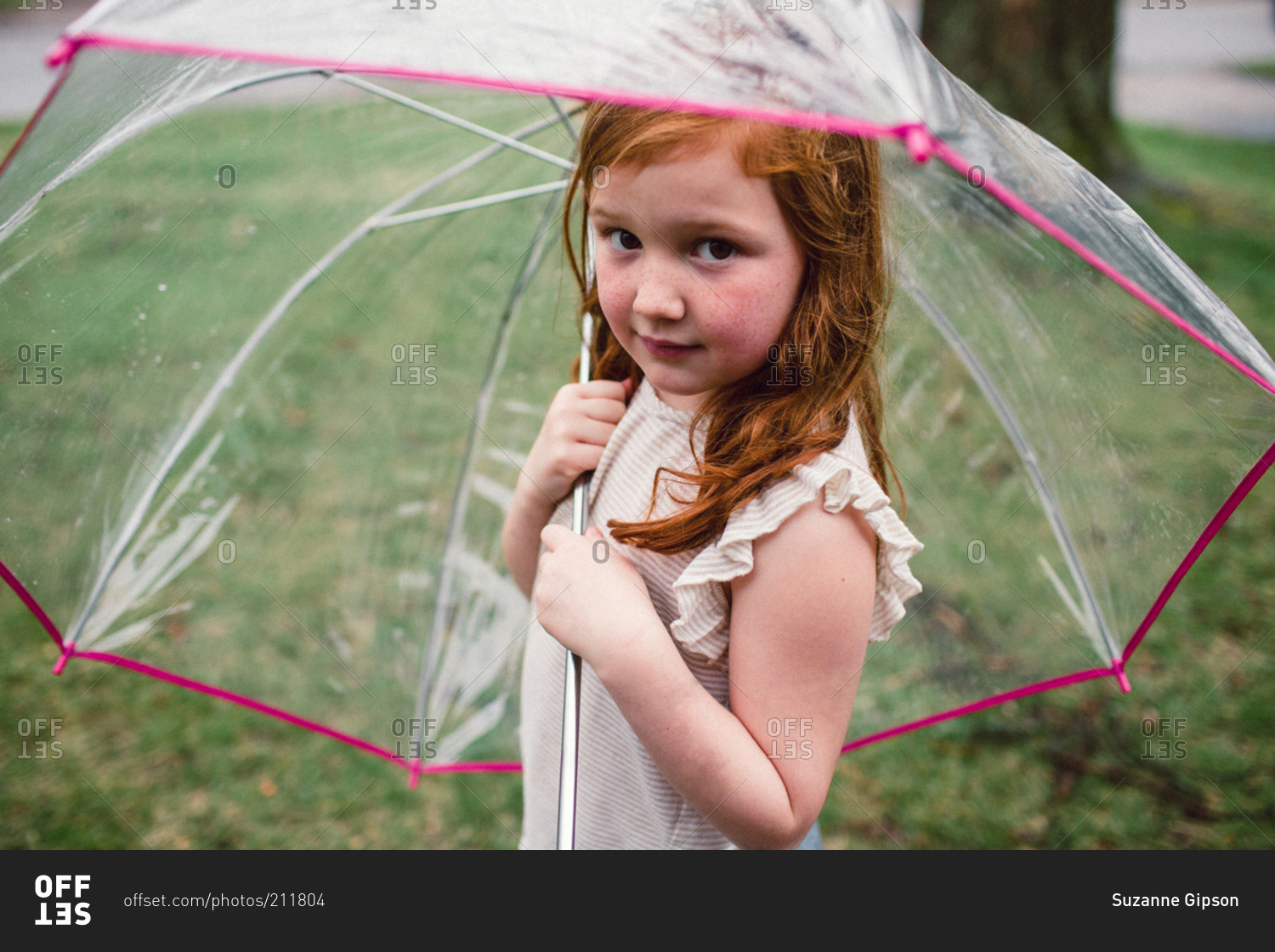 A little girl under a bucket umbrella