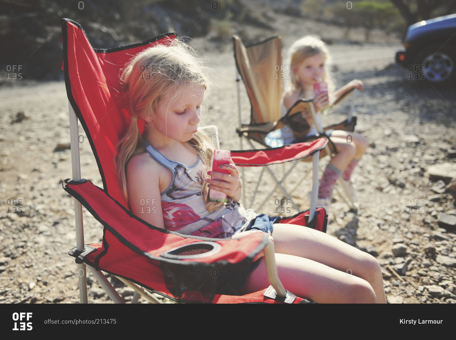 Twin sisters drinking in camping chairs