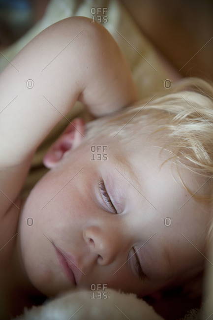 A blonde boy taking a nap