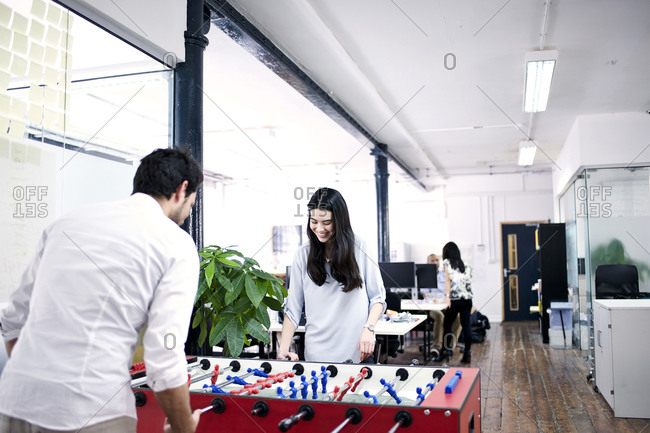 Coworkers playing foosball in office