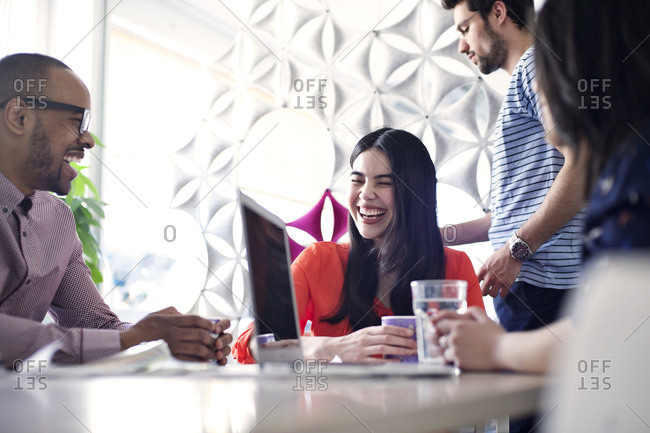 Coworkers laughing during meeting in office