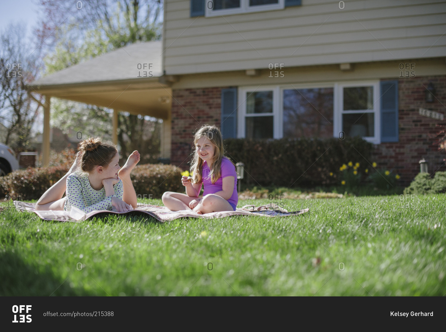 Two girls laying on blanket in front yard