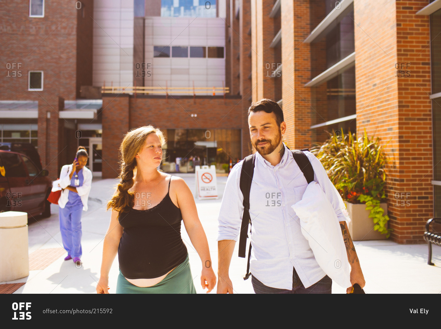 A husband and his pregnant wife walk towards a hospital