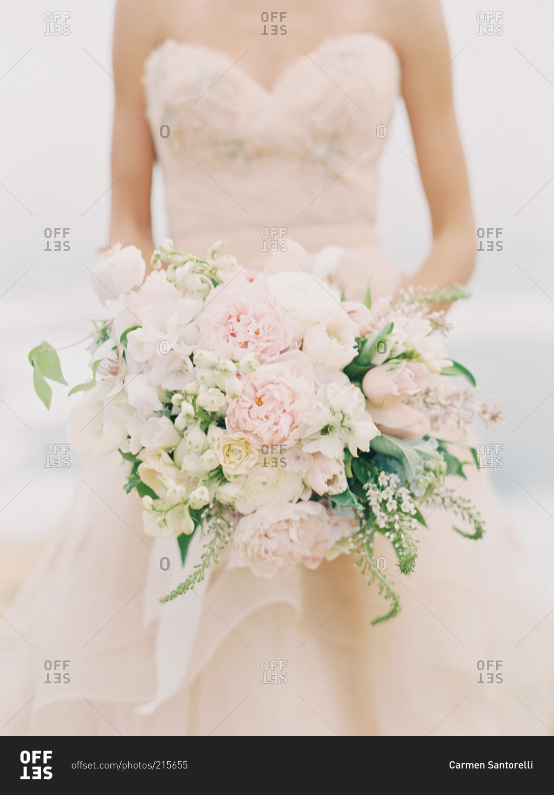 A bride in a pale pink dress holds a bouquet