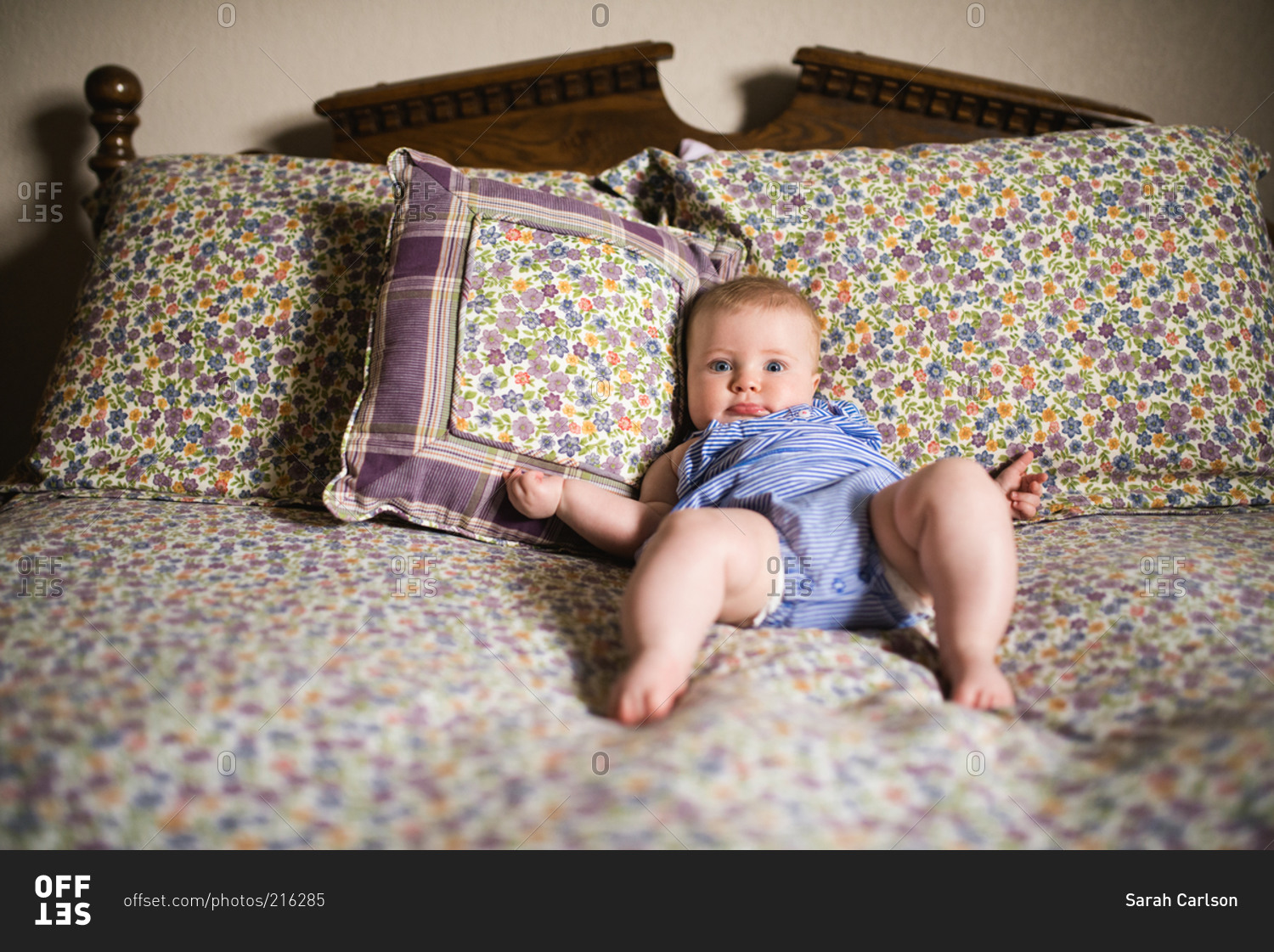 Baby propped up on bed pillows stock photo OFFSET