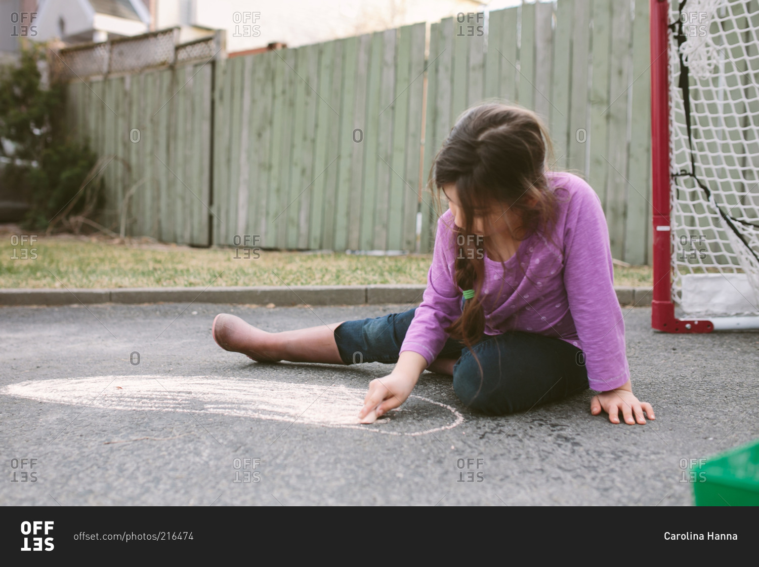 Young girl drawing on pavement with chalk