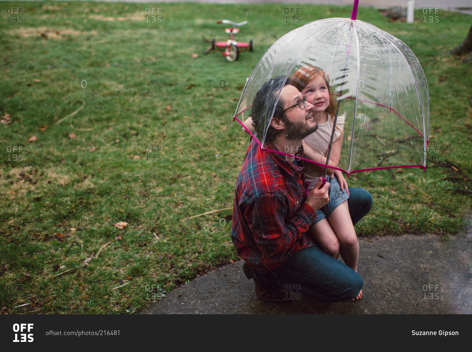 Dad and daughter looking up while underneath umbrella in rain
