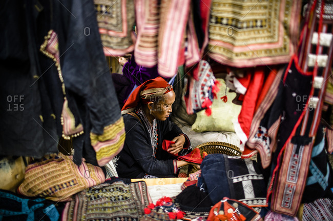 Red Dzao woman sells embroidered goods at market