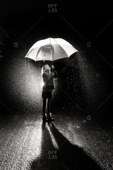 A little girl smiles while holding an umbrella in pouring rain