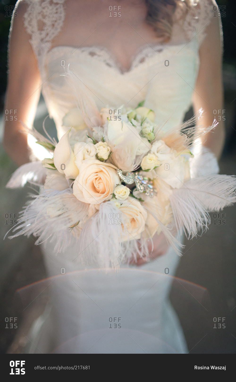 A bride holds her bouquet filled with feathers and roses