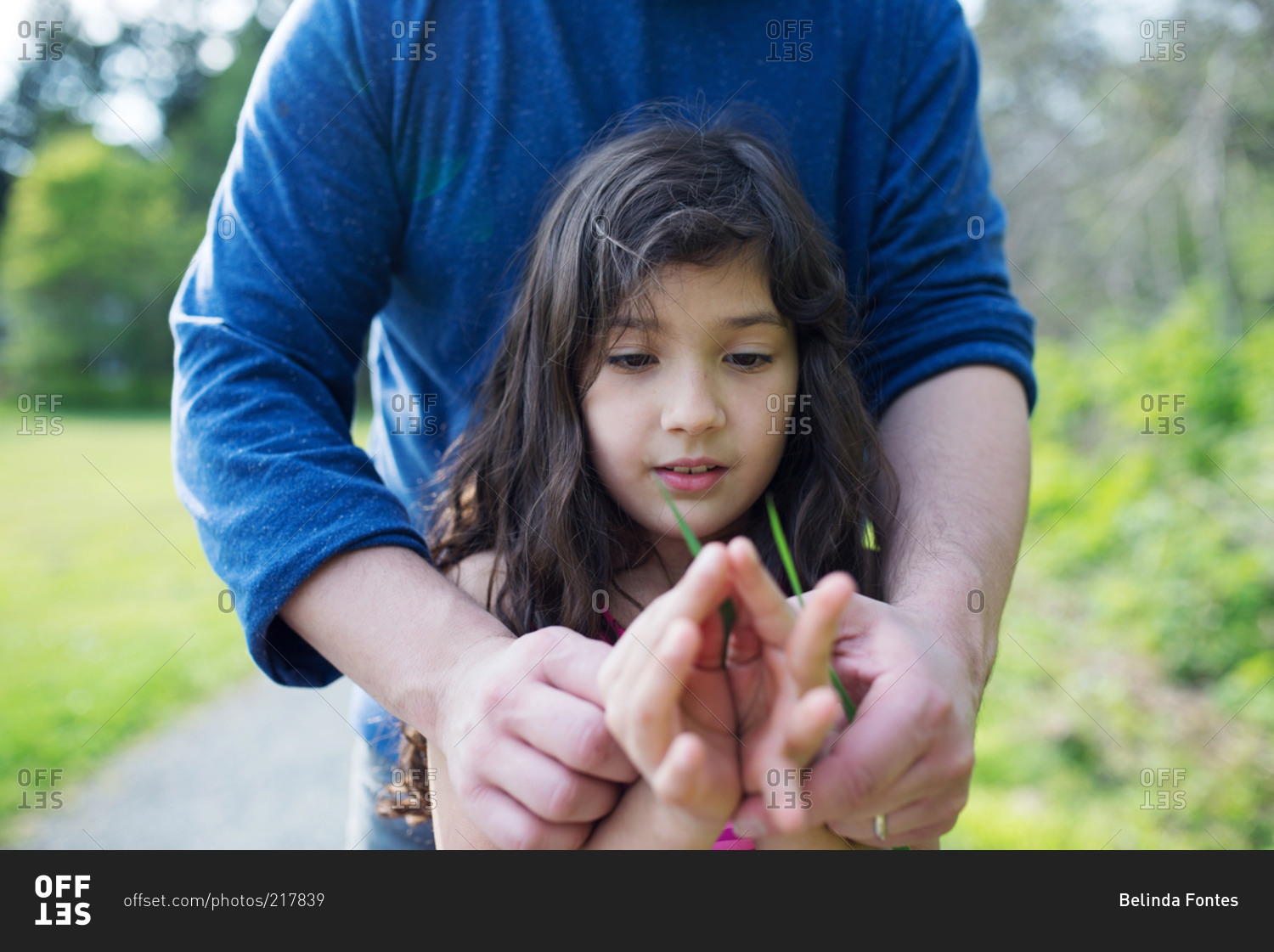 A dad shows his daughter how to whistle a blade of grass stock photo