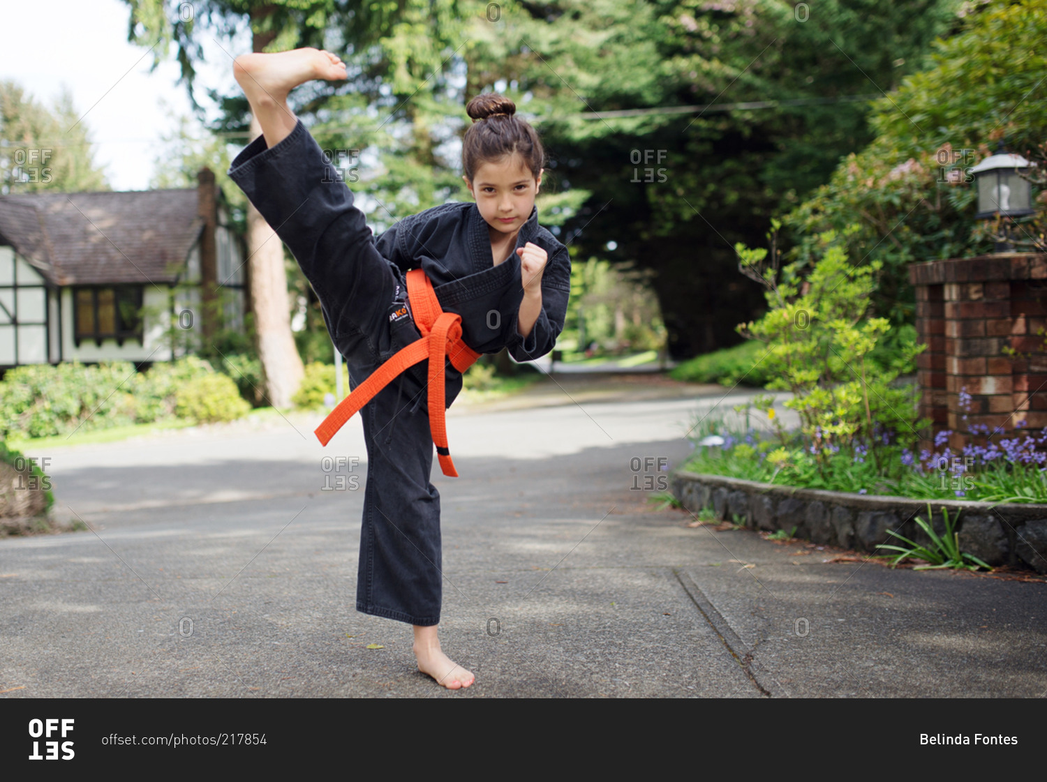 A girl wearing an orange belt practices a karate kick