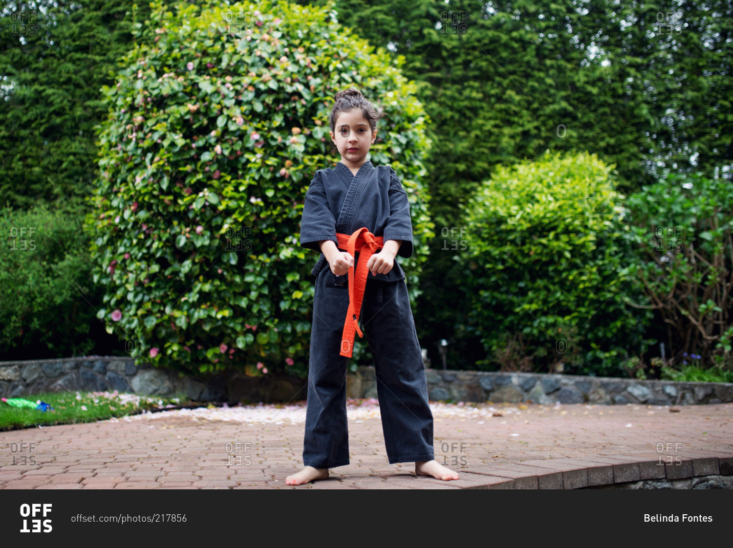 A girl in a karate uniform stands with her fists in front of her