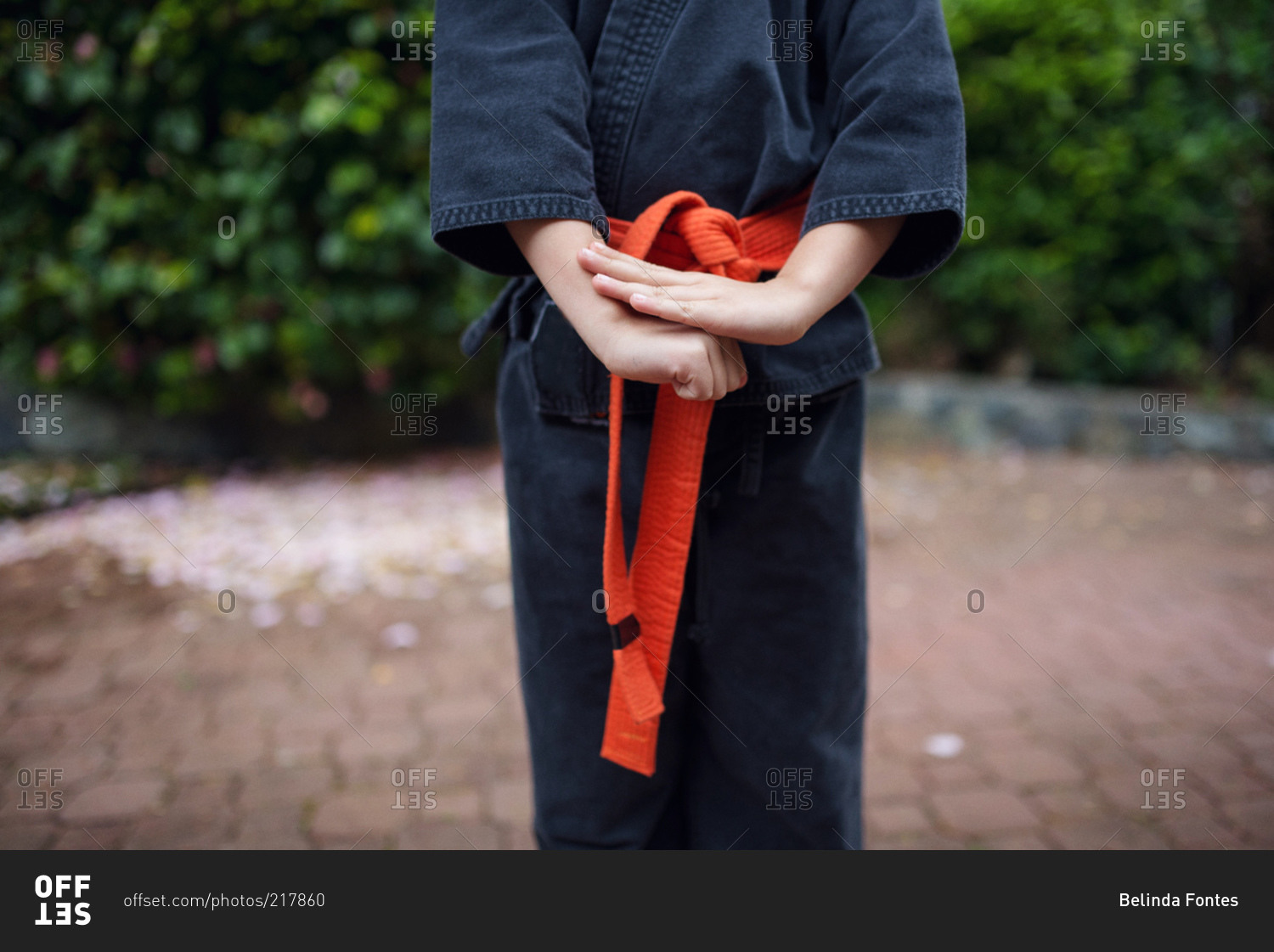 A girl in a karate uniform covers her fist with her palm