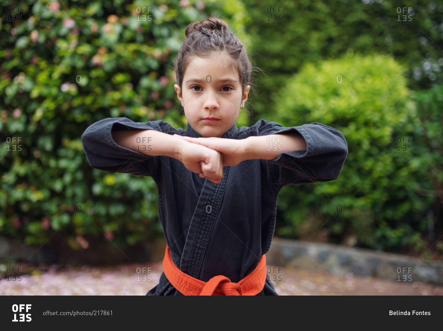 A girl in a karate uniform raises her fist to her chin
