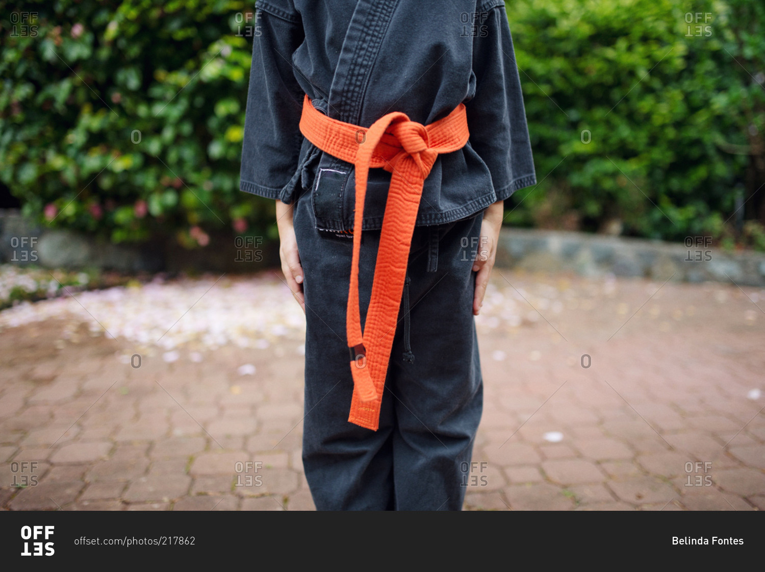 Mid-section of girl in a karate uniform wearing an orange belt