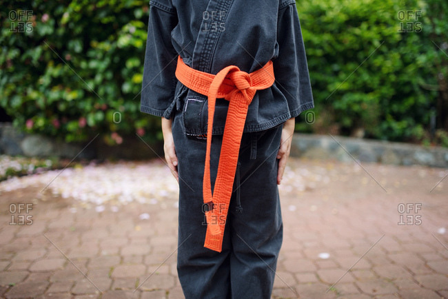 of girl in a karate wearing an orange belt stock photo - OFFSET