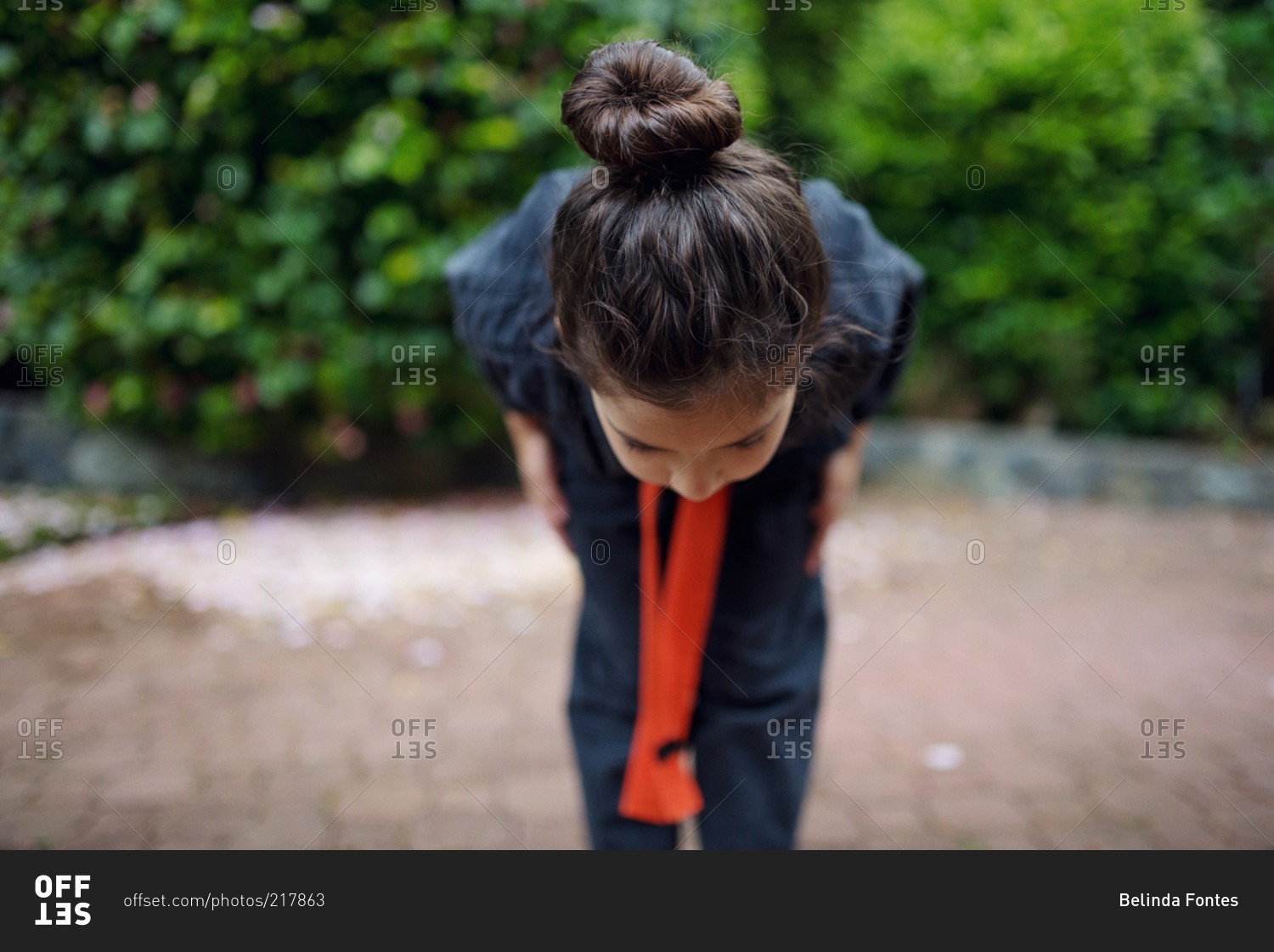 A little girl in a karate uniform bows
