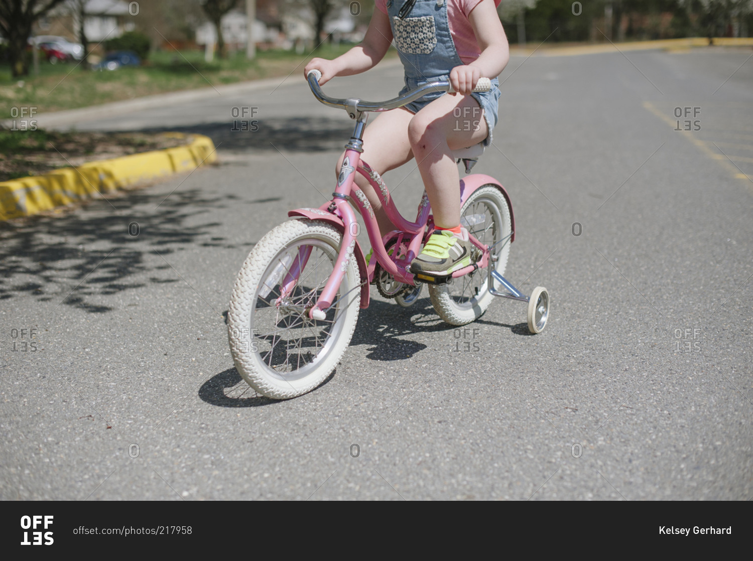 Closeup of a child riding a pink bicycle with training wheels