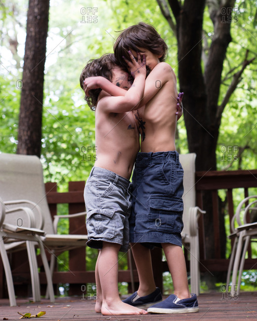 Two young boys grabbing each other and smearing one another with paint